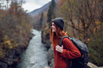 Young woman looking away while standing on tree during winter