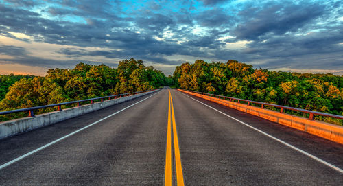 Road by trees against sky