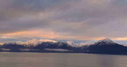 Scenic view of lake and snowcapped mountains against sky during sunset