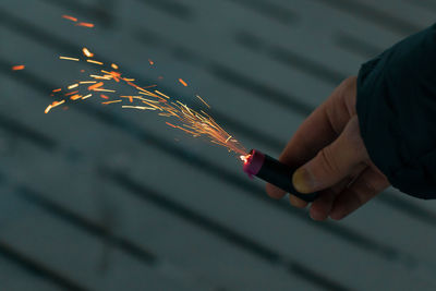 Cropped hand holding sparkler at night