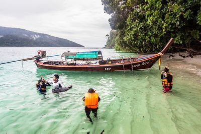 Rear view of people on boat against sky