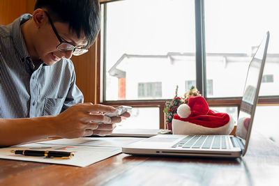 Woman using phone while sitting on table