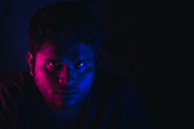 Close-up portrait of young man in darkroom