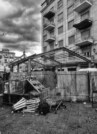 Empty chairs by building against sky in city