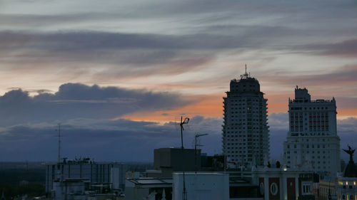 Buildings in city against cloudy sky during sunset