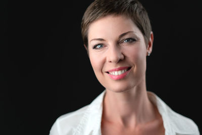 Close-up portrait of young woman against black background