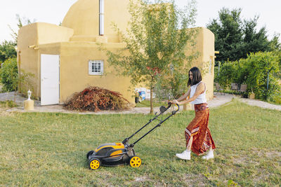 Mature woman mowing backyard lawn