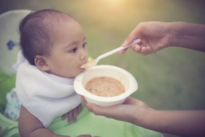 Cropped hands of person feeding baby