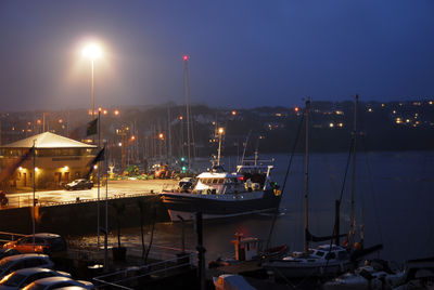 Boats moored in harbor at night