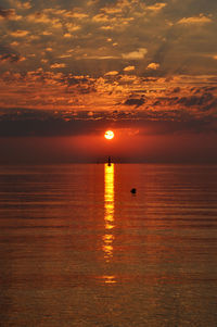 Scenic view of sea against cloudy sky during sunset