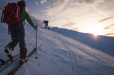Two people backcountry skiing in iceland at sunrise