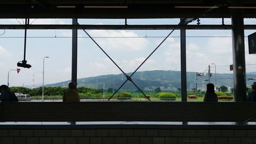 Scenic view of mountains seen through glass window against sky