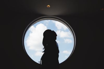 Side view of silhouette woman standing by window