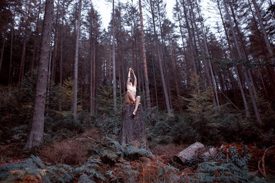 Woman standing by trees in forest