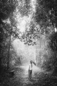 Woman with umbrella standing at forest