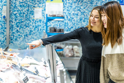 Couple of young multi-ethnic cute women are doing fish shopping at the supermarket