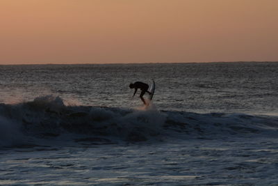 Silhouette man standing on beach against clear sky during sunset