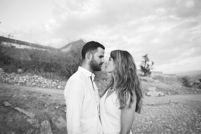 Side view of young couple looking each other face to face while standing on land