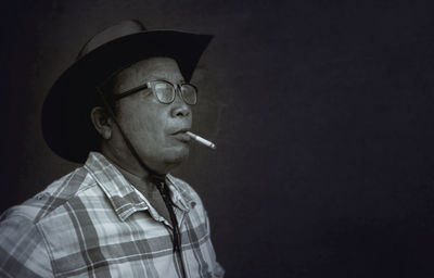 Side view of man smoking cigarette against black background