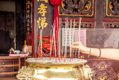 Hand lights a candle in front of a buddhist temple 