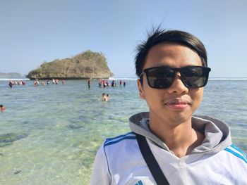 Portrait of man in sunglasses at beach against sky