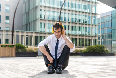 Side view of young man standing against buildings