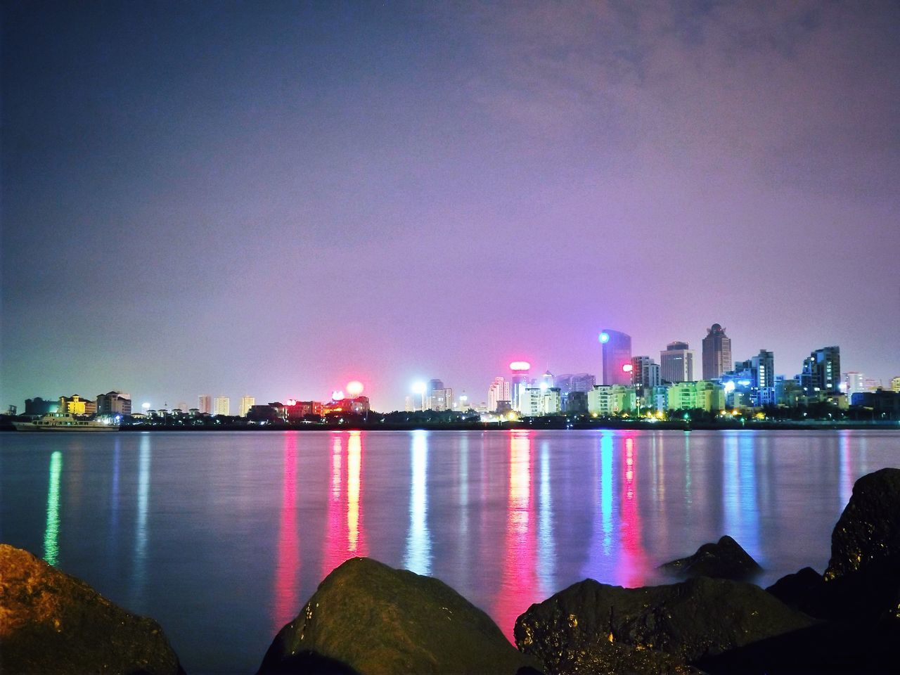 illuminated, night, water, building exterior, city, architecture, built structure, cityscape, reflection, copy space, sea, waterfront, clear sky, sky, river, skyscraper, multi colored, lake, urban skyline, outdoors