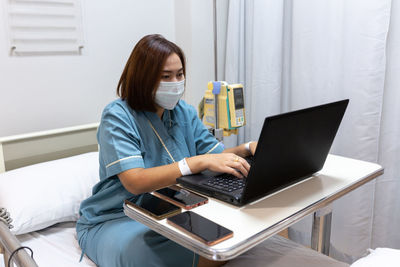 Woman using phone while sitting on table