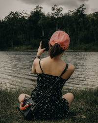 Woman holding ice cream by lake against trees