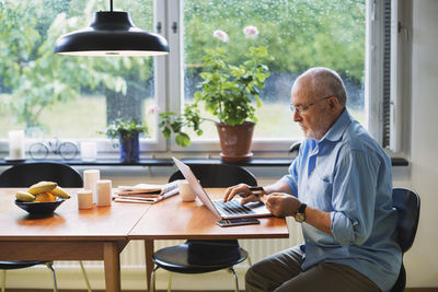 Side view of senior man using credit card for online shopping at home