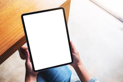 Midsection of woman using digital tablet on table