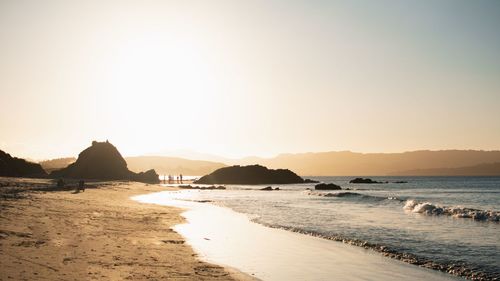 Scenic view of beach against clear sky during sunset