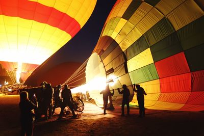 People filling gas in hot air balloon at night
