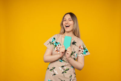 Portrait of a smiling young woman against yellow background