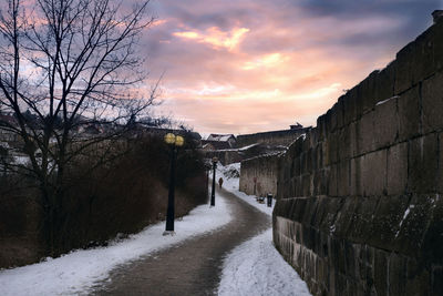 Road amidst buildings against sky during sunset