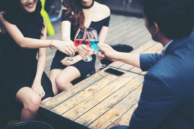 Rear view of young man with happy friends toasting drinks at bar