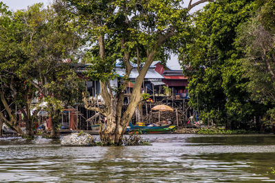 House by river amidst trees and building