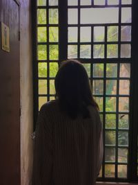 Rear view of woman standing against window