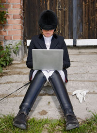 Young woman in riding clothes using laptop