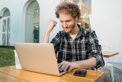 Young man using mobile phone while sitting on table