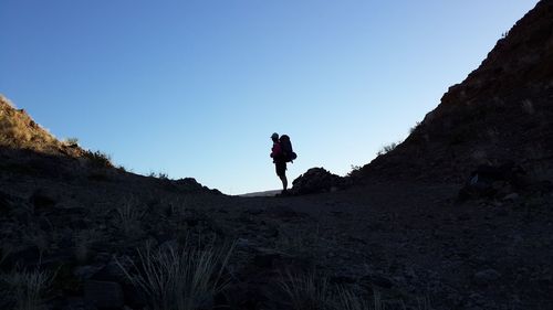 Low angle view of man on cliff against clear sky