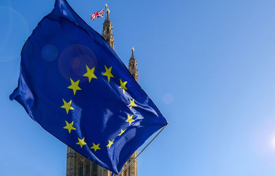 Low angle view of flags against clear blue sky