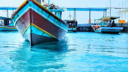 Boats moored at harbor against clear blue sky