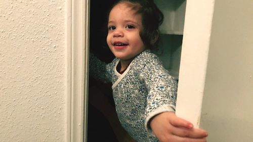 Portrait of cute girl standing against window
