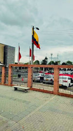 Flag on footpath by building against sky