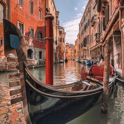 Boats moored in canal amidst buildings in city