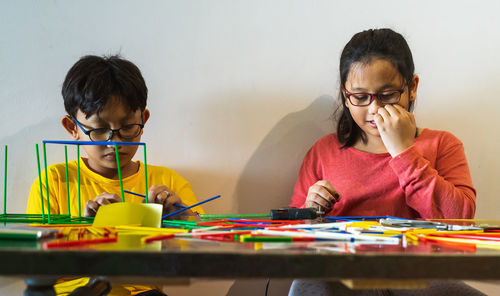 Children constructing colorful plastic sticks with glue gun. building figures, mathematics.