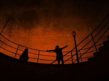 Silhouette people playing on bridge against sky during sunset