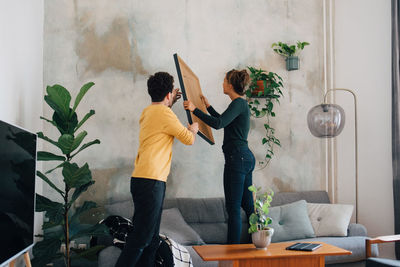 Young couple standing by potted plant at home