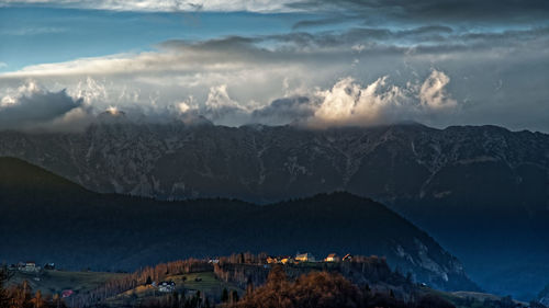 Scenic view of town by mountains against sky at dusk